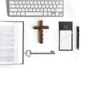 Flat lay: notebook, Bible, wooden cross, keyboard, silver key and pink, purple, violette, red Gerbera flower with petals Royalty Free Stock Photo