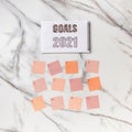 Flat lay of notepad with words Goals 2021, colorful sticky notes, o`clock, pen and pen case