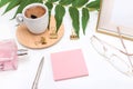 Flat lay, office desk, top view. Workspace with a coffee mug, an angry plant leaf, a perfume bottle, gold glasses and a pen, and a Royalty Free Stock Photo