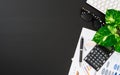 Flat lay office desktop work space of wireless keyboard, report graph and charts, pen, calculator and Glasses on black desk table