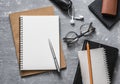 Flat lay office workplace. Business or education accessories - blank notepad glasses, pens, pencils, headphones on grey background