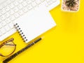 Flat lay of office yellow desktop with blank notepad, pen and eyeglasses with cactus. Top view with space for text. Royalty Free Stock Photo