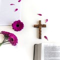 Flat lay: open Bible, wooden cross, open journal on white background and pink, purple, violette, red Gerbera flower with petals Royalty Free Stock Photo