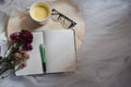 Flat lay of an open blank notebook, pen, eye glasses, a cup of coffee and purple flowers on a circular wooden table Royalty Free Stock Photo