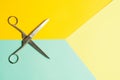Flat lay of opened scissors over turquoise blue and yellow background. conceptual photo of cutting scissors with central