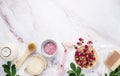 Flat lay with organic sea salt with dried rose flowers, soap, candle, brush and gua sha on a pink marble background. The concept Royalty Free Stock Photo