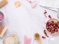 Flat lay with organic sea salt with dried rose flowers, soap, candle, brush and gua sha on a pink marble background in frame. The Royalty Free Stock Photo