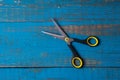 A pair of used children scissors against old blue wooden background