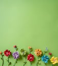 Flat lay of the paper colorful handmade flowers on a green background