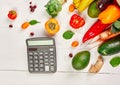 Flat lay paper shopping bag with assortment of fresh vegetables and fruits and calculator Royalty Free Stock Photo