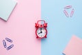 Flat lay on a pastel pink and blue background with a Notepad paperclip red alarm clock Royalty Free Stock Photo