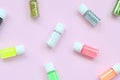 A flat lay pattern with colorful glitter bottles lies on pastel pink background