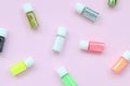 A flat lay pattern with colorful glitter bottles lies on pastel pink background