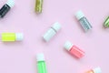 A flat lay pattern with colorful glitter bottles lies on pastel pink background