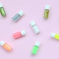 A flat lay pattern with colorful glitter bottles lies on pastel pink background