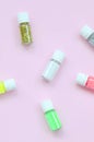 A flat lay pattern with colorful glitter bottles lies on pastel pink background