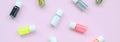 A flat lay pattern with colorful glitter bottles lies on pastel pink background