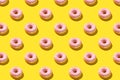 Flat lay pattern of tasty pink donut on yellow background