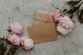 Flat lay peony flowers with craft card and envelope.