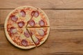 Flat lay pepperoni pizza on rustic wooden background. Pizza salami cut in slices. Fast food, junk food concept.