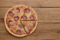 Flat lay pepperoni pizza isolated on rustic wooden background. Pizza salami cut in slices. Fast food, junk food concept.