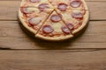 Flat lay pepperoni pizza isolated on rustic wooden background. Pizza salami cut in slices. Fast food, junk food concept.