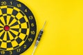 Flat lay of perfect black darts with dartboard on solid yellow background with copy space using as only one business chance to