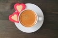 Flat lay photo of an espresso coffee with two heart shaped cookies served on dark brown wooden table Royalty Free Stock Photo