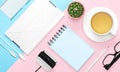 Flat lay photo of office desk with case for phone and tablet, notebook, tea mug, pencil, cactus, pink and blue background