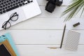 Frame made of laptop, eyeglasses, palm leaf and notebook on white wooden background. Flat lay business mockup