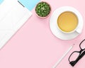 Flat lay photo of office desk with tablet computer, tea mug, pencil, cactus, glasses, pink and blue background