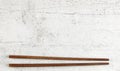 Flat lay photo - pair of dark wood chopsticks on white board. Wide banner for Asian or Chinese food, space for text above