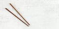 Flat lay photo - pair of dark wood chopsticks on white board. Wide banner for asian / chinese food, space for text on right