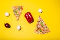 Flat lay photo of two pizza slices and few vegetables isolated on yellow background Royalty Free Stock Photo