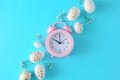 Flat lay photo of white gold eggs, gypsophila flowers on pastel blue background and pink alarm clock Royalty Free Stock Photo