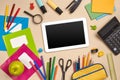 Flat lay photo of workspace desk with school accessories or office supplies on pink background.