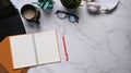 Flat lay photo of workspace with empty notebook, tablet, eye glasses, headphone, and coffee cup on marble background. Royalty Free Stock Photo