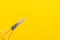 Flat lay photo of yellow scissors on the yellow background with copy space