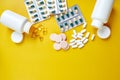 Flat lay of pills, fish oil, vitamins on yellow background