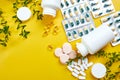 Flat lay of pills, fish oil, vitamins on yellow background