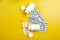 Flat lay of pills, fish oil, vitamins on yellow background