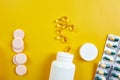 Flat lay of pills, fish oil, vitamins on yellow background