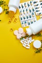 Flat lay of pills, fish oil, vitamins on yellow background