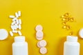 Flat lay of pills, fish oil, vitamins on yellow background