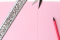 Flat lay: pink paper with a straight line drawn in pencil, silver ruler and scissors. Making a postcard in an envelope for