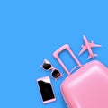 Flat lay pink suitcase, sunglasses, smartphone and toy airplane isolated on blue