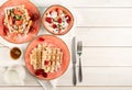 Flat lay of plates with Belgian waffles with fresh stawberry on white wooden background