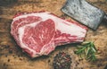 Raw beef steak rib-eye with seasoning and knife, rustic background Royalty Free Stock Photo