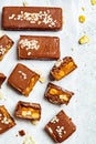 Flat lay of raw vegan chocolate and caramel bars, white background, top view. Healthy desserts concept