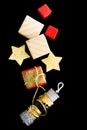 Flat lay Red, gold and beige christmas gifts with ribbons and foil stars on black background